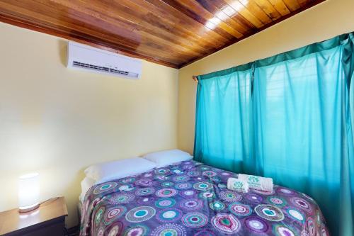 a bedroom with a bed and a blue curtain at Princesa Angienelle in Caye Caulker