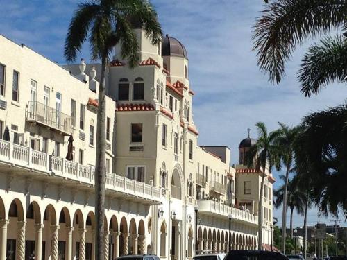 Hemingway Suites at Palm Beach Hotel Island في بالم بيتش: مبنى ابيض كبير امامه نخلة