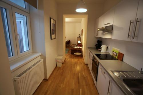 cocina con armarios blancos y suelo de madera en Casa Nostra - Ruhige Stadtwohnung mit Balkon, en Viena