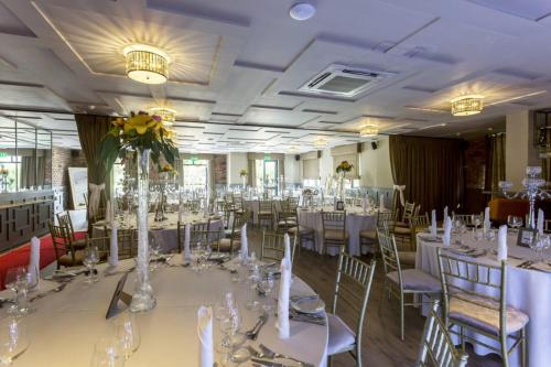 a banquet hall with white tables and chairs at The Village Hotel, Bar and Restaurant in Bettystown