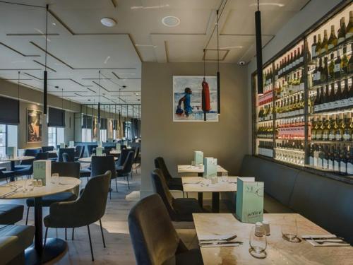 a restaurant with tables and chairs and wine bottles at The Village Hotel, Bar and Restaurant in Bettystown