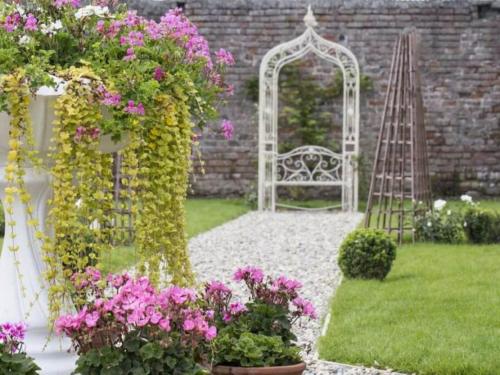 a garden with a white arch and pink flowers at The Village Hotel, Bar and Restaurant in Bettystown