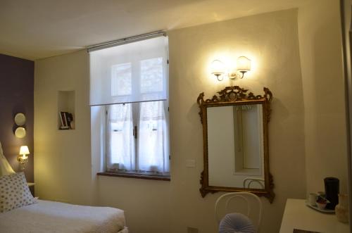 1 dormitorio con espejo, cama y ventana en Il Nido Di Anna, en San Gimignano