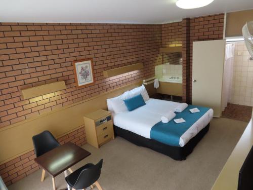 a bedroom with a bed and a brick wall at East West Motel Ceduna in Ceduna