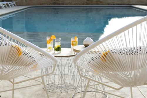 a table and chairs next to a swimming pool at Le Vieux Castillon in Castillon-du-Gard