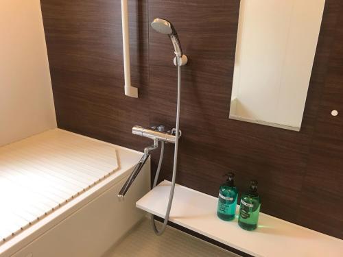 una ducha con 2 botellas en un banco en el baño en HIBARI GUESTHOUSE, en Sendai