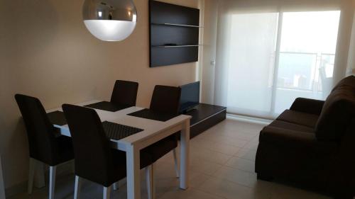 Una sala de estar con una mesa y sillas y un sofá. en Apartamento con fantásticas vistas al mar, en Benidorm
