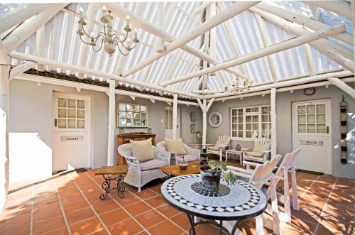 a conservatory with a wooden ceiling and a table and chairs at Lodge on Main Guest House and Conference Centre in Port Elizabeth