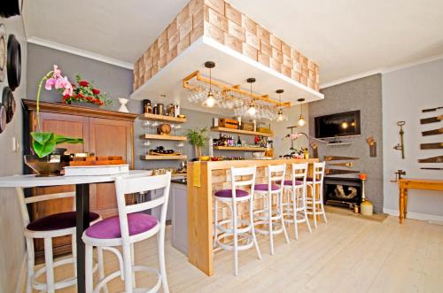 a kitchen with a bar with stools and a fireplace at Lodge on Main Guest House and Conference Centre in Port Elizabeth