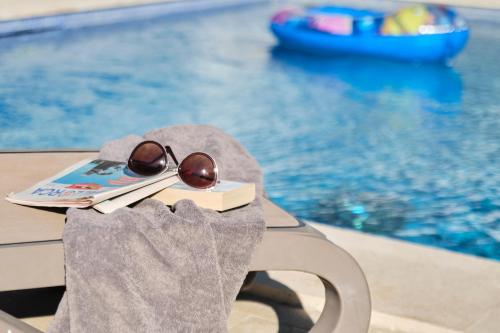 a pair of sunglasses and a book next to a swimming pool at Duvabitat Apartments in Port de Pollensa
