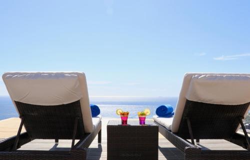 two chairs sitting on a deck with flowers in them at Atlanticview Cape Town Boutique Hotel in Cape Town