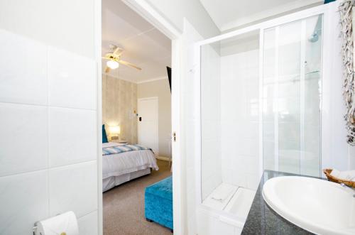 a bathroom with a sink and a bedroom at Lodge on Main Guest House and Conference Centre in Port Elizabeth