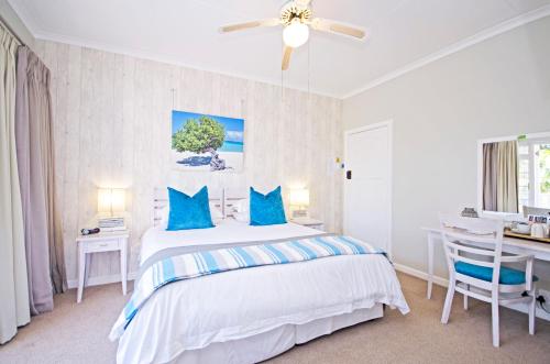 a bedroom with a bed with blue pillows and a desk at Lodge on Main Guest House and Conference Centre in Port Elizabeth
