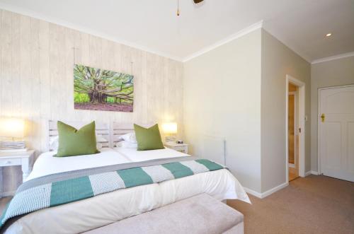a bedroom with a large white bed with green pillows at Lodge on Main Guest House and Conference Centre in Port Elizabeth