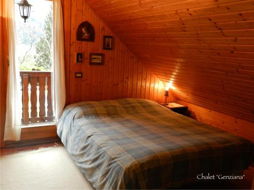 ein Schlafzimmer mit einem Bett in einer Hütte mit einem Fenster in der Unterkunft Agriturismo Bosco Di Museis in Cercivento