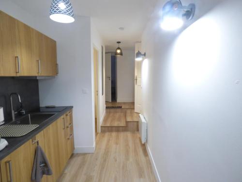 une cuisine avec des murs blancs et des placards en bois ainsi qu'un couloir dans l'établissement Luz et vous , T 3, classé 2 étoiles, à Luz-Saint-Sauveur