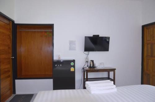 a room with a bed with a refrigerator and a television at Nok Chan Mee Na in Chom Thong