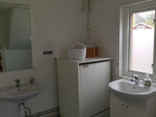 ein Bad mit 2 Waschbecken, einem Spiegel und einem Fenster in der Unterkunft B&B Parkgården Leksand in Leksand