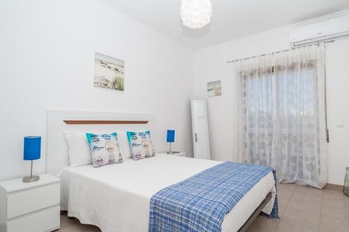 ポルティマンにあるApartamentos Castelos da Rochaの白いベッドルーム(青い枕の大型ベッド付)