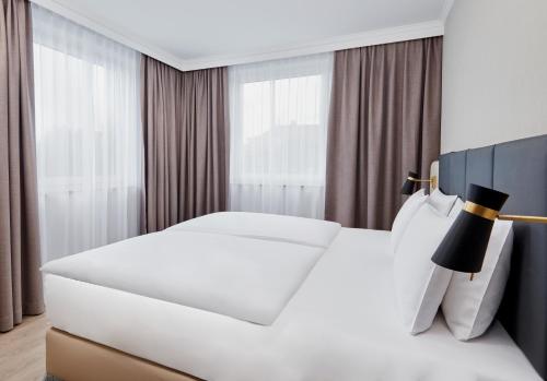 a white bed in a hotel room with curtains at Crowne Plaza Hamburg-City Alster by IHG in Hamburg
