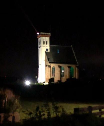een gebouw met 's nachts een lichttoren bij Bed en Breakfast kamers en meer Het Spookhuis in Den Hoorn