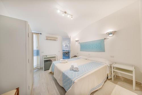 a white bedroom with a bed and a desk at Hotel Le Mimose in San Teodoro