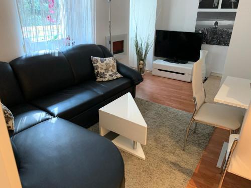 - un salon avec un canapé en cuir noir et une télévision dans l'établissement Dani Apartment, à Rijeka