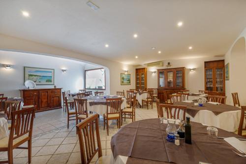a restaurant with tables and chairs in a room at Hotel Le Mimose in San Teodoro