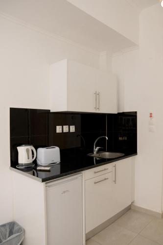 a kitchen with white cabinets and a sink at Jessica's Studios & Apartments in Kavos