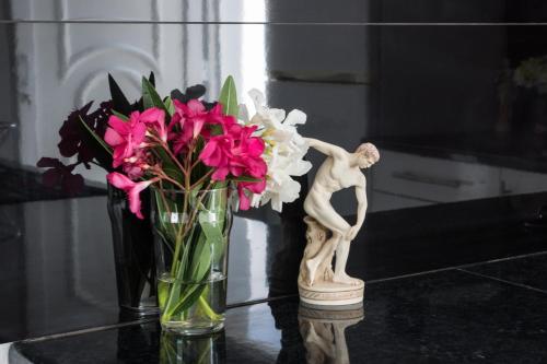 a vase with a statue and flowers on a table at Jessica's Studios & Apartments in Kavos