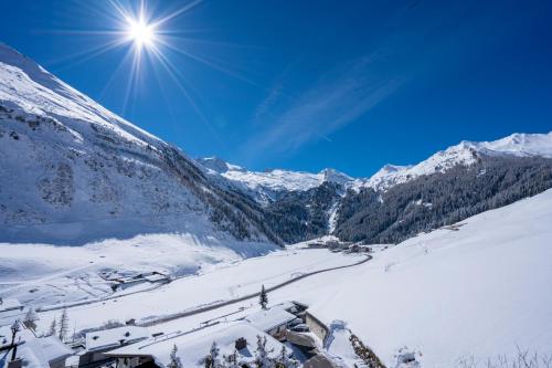 a snow covered mountain with the sun in the sky at Alpenbad Hotel Hohenhaus in Tux