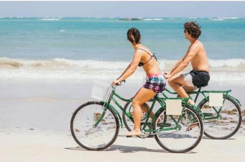 two people riding bikes on the beach at Pousada Vale Encantado in São Miguel dos Milagres