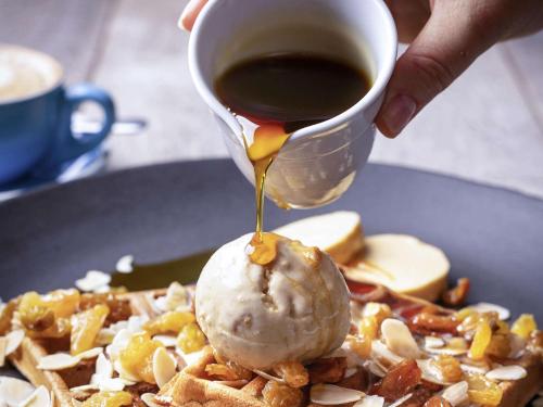 a person drizzling syrup onto a plate of waffles at Sofitel Noosa Pacific Resort in Noosa Heads
