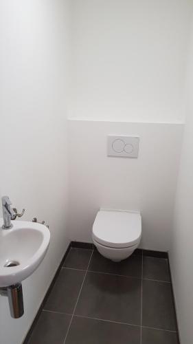 a bathroom with a white toilet and a sink at Appart Hotel Nivelles in Nivelles