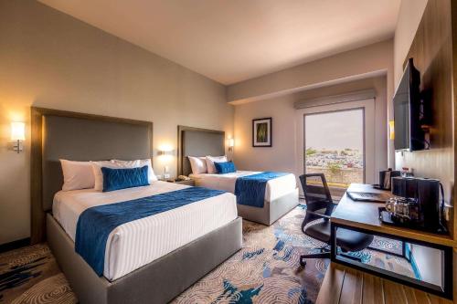 エルモシージョにあるComfort Inn Hermosillo Aeropuertoのベッド2台とテレビが備わるホテルルームです。