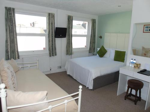 1 dormitorio con 2 camas, escritorio y espejo en Carrington Guest House, en Paignton