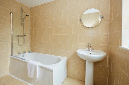een badkamer met een bad, een wastafel en een spiegel bij Listers Lodge in Halifax