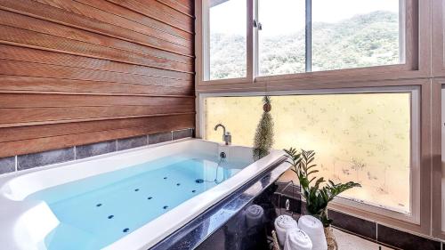 a bath tub in a room with a window at Mokkoji Pension in Hadong