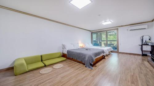 a bedroom with a bed and a green couch at Mokkoji Pension in Hadong