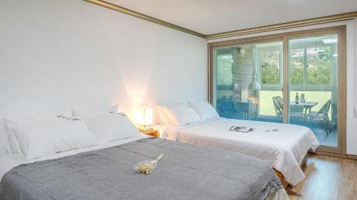 a bedroom with two beds and a table and a window at Mokkoji Pension in Hadong