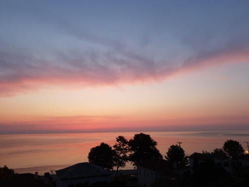 a sunset over the ocean with houses and trees at Aeolos Hotel & Villas - Pelion in Chorefto