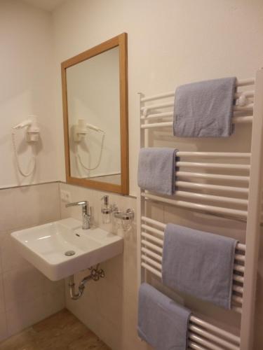 y baño con lavabo, espejo y toallas. en Haus Alpenflora, en Flirsch