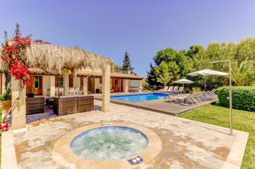 a house with a swimming pool and a thatch roof at Villa Ponent by Sealand Villas in Pollença