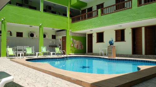 a large swimming pool in a hotel with chairs and tables at Pousada Ouriço in Porto De Galinhas