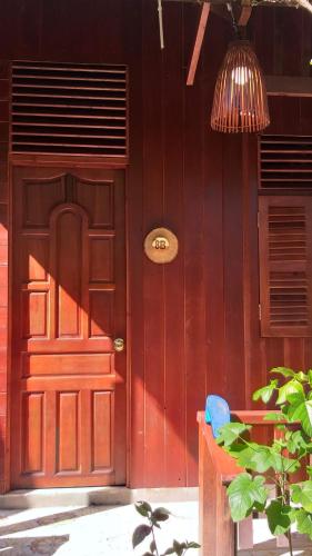 a red door on a house with a lamp at Homestay Xóm Dừa Nước in Ben Tre