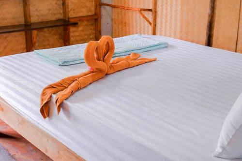 a white bed with an orange towel on it at Asama Bungalow in Ko Lanta
