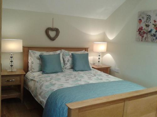 a bedroom with a bed with blue pillows and two lamps at Thornthwaite Farm in Broughton in Furness