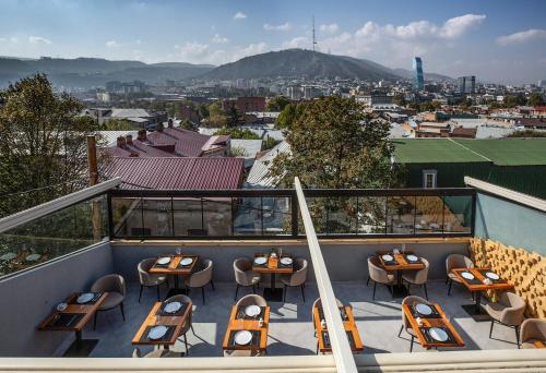 a balcony with tables and chairs and a view of a city at Ornament Boutique Hotel in Tbilisi City