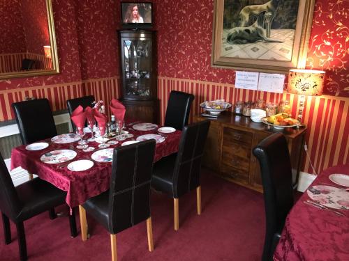 a dining room with a table and chairs and red walls at Redwood Lodge in Westbury
