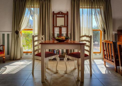 una mesa de comedor con sillas y un bol de fruta. en Berluda Farmhouse and Cottages, en Oudtshoorn